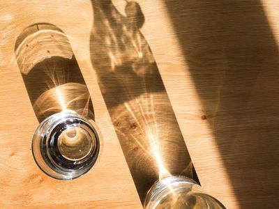 Glass of water on a dark table reflecting light